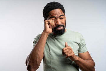 Black man rubbing eyes with discomfort, irritated and tired, experiencing eye itching and burning,...