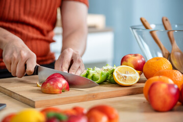Hand chef knife cut and slice fresh Vegetables baby cos salad on wood board table .Make Salad Organic Vegetables mix lunch with green vegetables and fruit at kitchen table on wood cutting board.