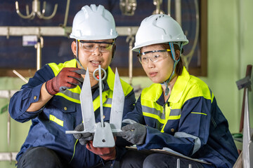 Marine Anchor Inspection: Two Engineers Teamwork Collaborating and Inspecting Small Anchor with Safety Gear on Precision Metal Component Team of Asian Engineers Verifying Marine Equipment.