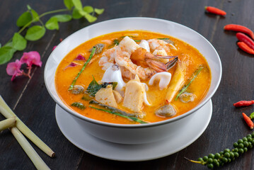 A bowl of Tom Yum soup with shrimp, squid, and mushrooms.