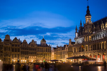 Historic illuminated buildings reflecting on wet stone in Grand Place, Brussels, Belgium at night, expressing architecture, European heritage and winter tourism atmosphere.