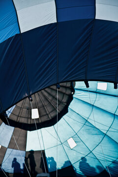 Interior view of a hot air balloon from below as it inflates, with geometric blue fabric shapes forming abstract patterns and textures related to adventure and outdoor travel.