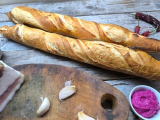 Freshly baked and sliced ​​French bread next to a delicious piece of lard on a cutting board