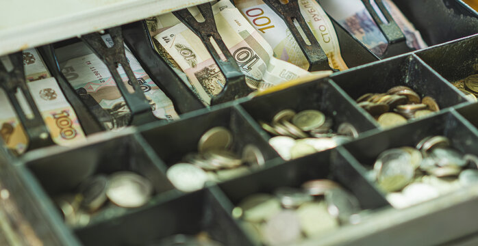 Currency in rubles fills a cash register drawer with organized notes and coins during a transaction at a retail checkout The setting reflects a typical shopping environment - Powered by Adobe