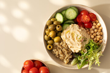 Colorful Buddha bowl with quinoa, hummus, chickpeas, vegetables. Healthy dish. Copy space