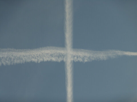 Two intersecting contrails form a cross in a clear blue sky, symbolizing aviation, travel, and atmospheric phenomena. - Powered by Adobe