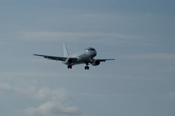 The airplane approaches the airport against a backdrop of clouds. The airplane is ready to land.