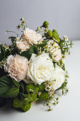 Bouquet of white roses, delicate pink carnations and varietal green carnations with raspberry branches and small daisy buds. Professional floral wedding arrangement on a white background