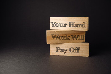 Inspirational wooden blocks with motivational phrase about hard work and success on dark background