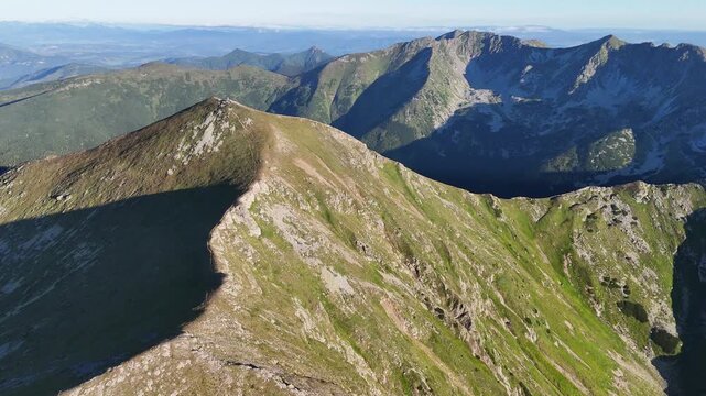 Aerial view of sharp mountain peaks with lush green grass cascading down their slopes, creating a striking contrast of textures and tones, ziar, zilina Region, Slovakia.