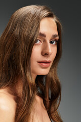 Naklejka premium Captivating young woman with flowing hair showcasing elegance and charm in soft lighting