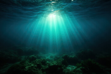 Obraz premium Sunlight rays penetrating deep underwater ocean surfaceUnderwater scene with beams of light and rocky seafloor