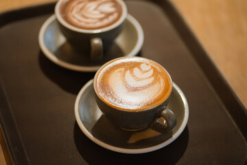 Two cups of coffee on black tray with beautiful latte art at cafe