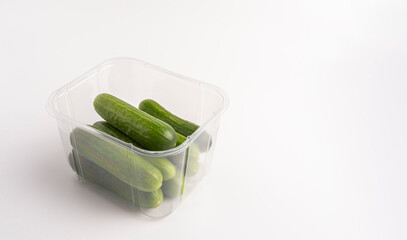 Fresh cucumbers in plastic container, isolated on white background.
