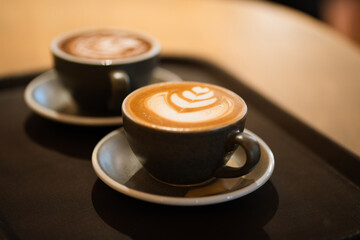 Side view of hot latte coffee with latte art in a black cup on wooden table
