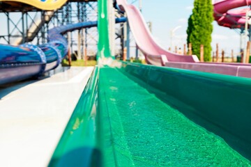 Obraz premium Aqua streams cascade through a verdant water slide at a vibrant park on a sunny day. Colorful slides twist into the distance, a playground for thrill-seekers ready for a cool escape