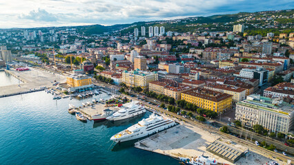 Fototapeta premium Rijeka city center and waterfront aerial view at sunset, panoramic view of the Kvarner Gulf in Croatia. Scenic harbor with boats, historic architecture, container terminal, canals, seafront promenade