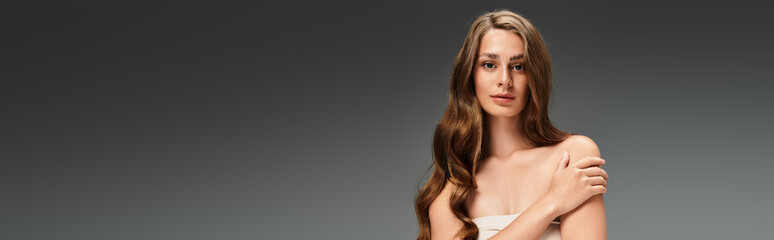 Naklejka premium Captivating young woman with flowing hair expressing natural beauty in a simple setting
