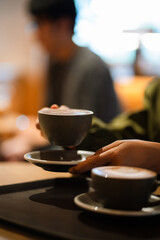 The morning sunlight falls on the table, beautiful shadows appear. Delicious breakfast.Women's hands hold a cup of hot latte coffee.	