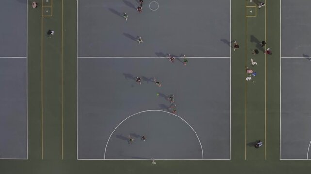 Aerial view of netball courts, with players, contrasting the grey courts and surrounding green areas, Madeley, Western Australia, Australia.