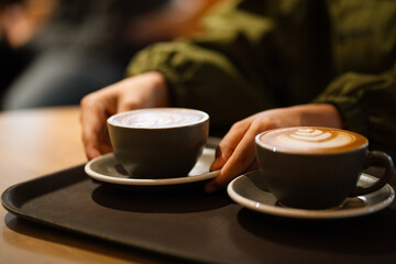 The morning sunlight falls on the table, beautiful shadows appear. Delicious breakfast.Women's hands hold a cup of hot latte coffee.