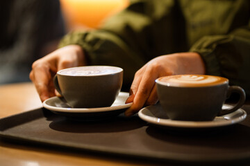 The morning sunlight falls on the table, beautiful shadows appear. Delicious breakfast.Women's hands hold a cup of hot latte coffee.