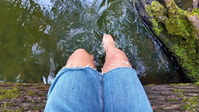 Peaceful riverbank relaxation: bare feet dangling over flowing water