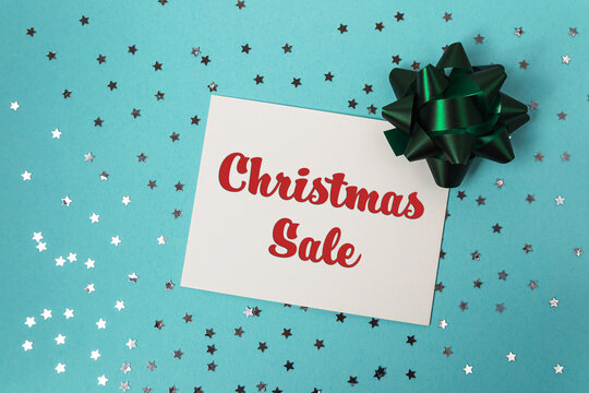 Festive holiday sale announcement card with decorative bow and sparkling stars on blue background