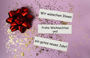 Festive red bow on purple background with glitter and holiday greeting cards for celebration