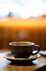 Side view of hot latte coffee a black cup on wooden table.