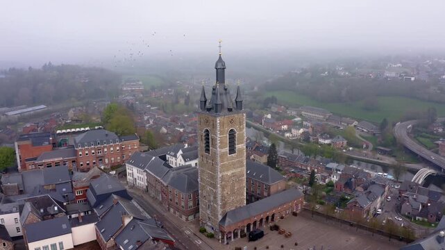 Aerial view of Thuin's buildings, with its tall tower dominating the skyline, all nestled amongst the soft, muted colors of the landscape, Thuin, Wallonia, Belgium.