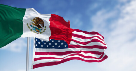 Mexico and US national flags waving on a clear day