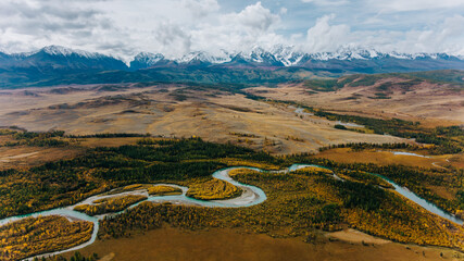 Aerial view of chuya river meandering through a valley in autumn, with colorful trees and the...