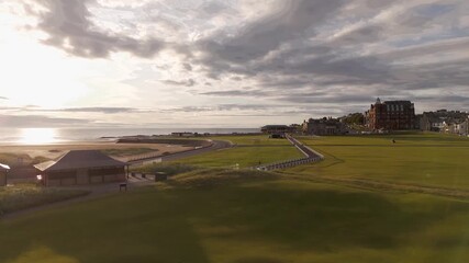 Aerial view of The Old Course golf, showcasing the lush green course contrasting with the buildings and the ocean, St Andrews, Scotland, United Kingdom.