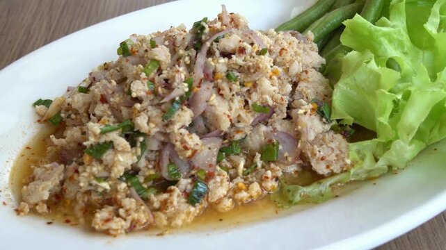 A plate of spicy thai larb salad with meat and fresh herbs