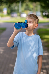 Teenage boy drinking water from sports bottle outdoors on a warm sunny day