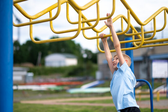 Blond boy hanging on monkey bars at outdoor playground