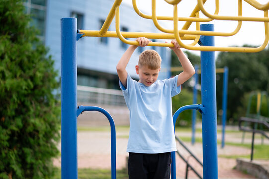 Blond boy hanging on monkey bars at outdoor playground
