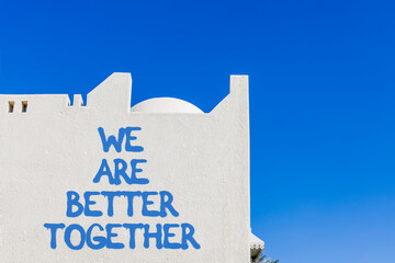 We are better together symbol. Concept words phrase We are better together on beautiful white wall. Beautiful white wall and blue sky background. Business We are better together concept. Copy space.