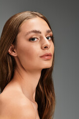 Fototapeta premium Young beautiful woman showcasing natural beauty in elegant studio setting with soft lighting
