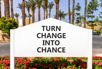 Turn change into chance symbol. Concept words phrase Turn change into chance on beautiful big white road sign. Beautiful palm blue sky background. Business Turn change into chance concept. Copy space.