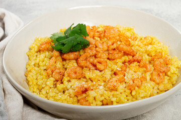 risotto with shrimp, in a bowl, on a textured surface, with a side dish of fresh coriander, homemade, no people,