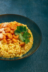 risotto with shrimp, in a bowl, on a textured surface, with a side dish of fresh coriander, homemade, no people,