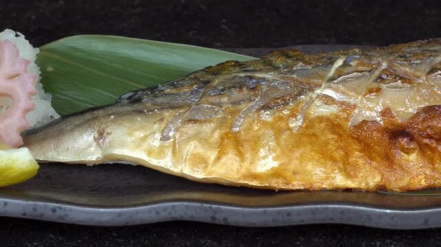Grilled saba fish is served with lemon and lotus root