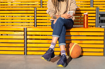 Woman resting on a bright yellow bench, looking at phone.