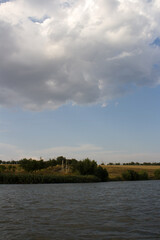 A body of water with trees and clouds in the sky