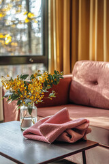 Cozy Autumn Home Interior with Yellow Flowers and Soft Pink Towel on Coffee Table