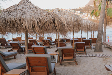 Beach relaxation area with straw umbrellas and sun loungers on sandy shore near the water