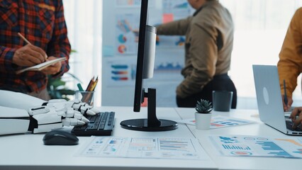 A vibrant office scene showcasing a robotic arm, laptop, and business charts while professionals engage in creative collaboration. Modern workspace inspires productivity and innovation.Noogenesis