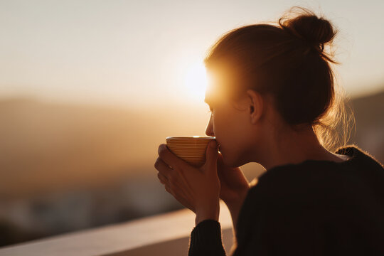 young woman enjoys her morning coffee on balcony basking in soft glow of early sunlight